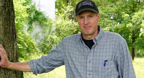 UNH Organic Dairy Research Farm manager Jason Scruton leans against a tree.